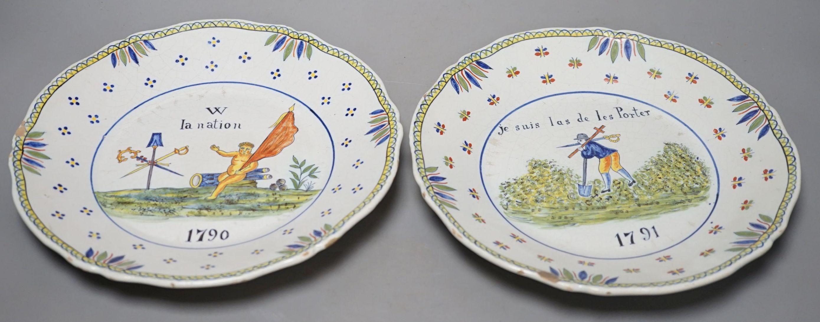A pair of French faience plates - ‘la nation’, 1790, and ‘je suis las de les Porter’, 1791 - 24cm diameter